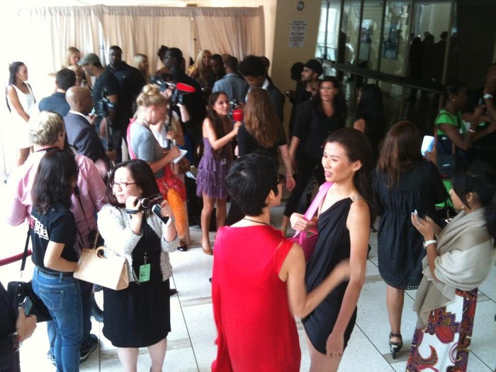 Người mẫu Xuân Lan (áo đỏ) bên cạnh thí sinh Thiên Trang và bà Quỳnh Trang tay cầm máy quay tại buổi trình diễn bộ sưu tập của NTK Nina Skarra trong Tuần lễ Thời trang Xuân New York 2013.